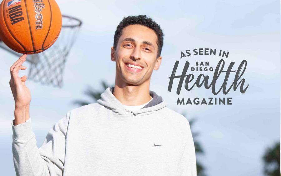 Bahrom Firozgary, MD, sports medicine physician at Scripps Clinic Torrey Pines, smiles on the basketball court as he balances a basketball on his finger. San Diego Health Magazine