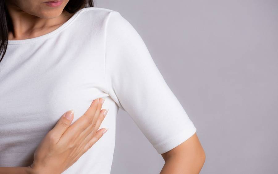 A woman feels her breast checking for any unusual lumps. She may have dense breast.