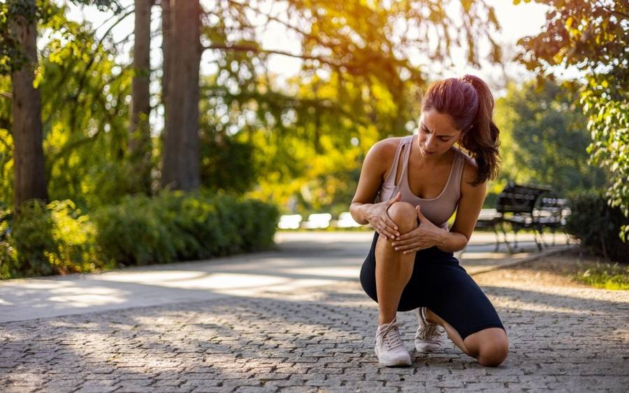 A runner rubs her knees after feeling pain during a workout. Could it be early onset knee osteoarthritis?