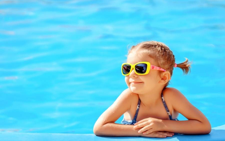 A little girl cools off in her family's swimming pool during a hot summer day.