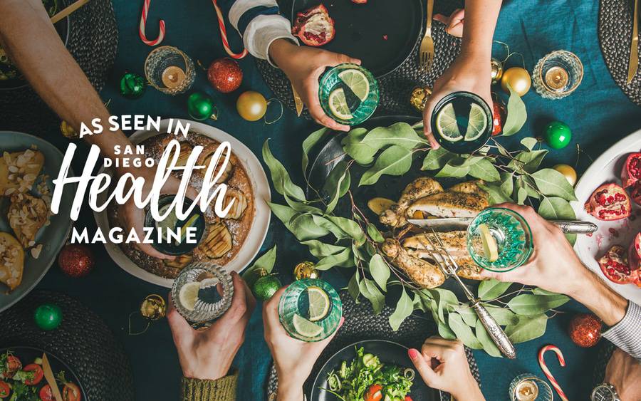 A festive holiday meal with healthy food displayed including pomegranates, turkey, salad and butternut squash.