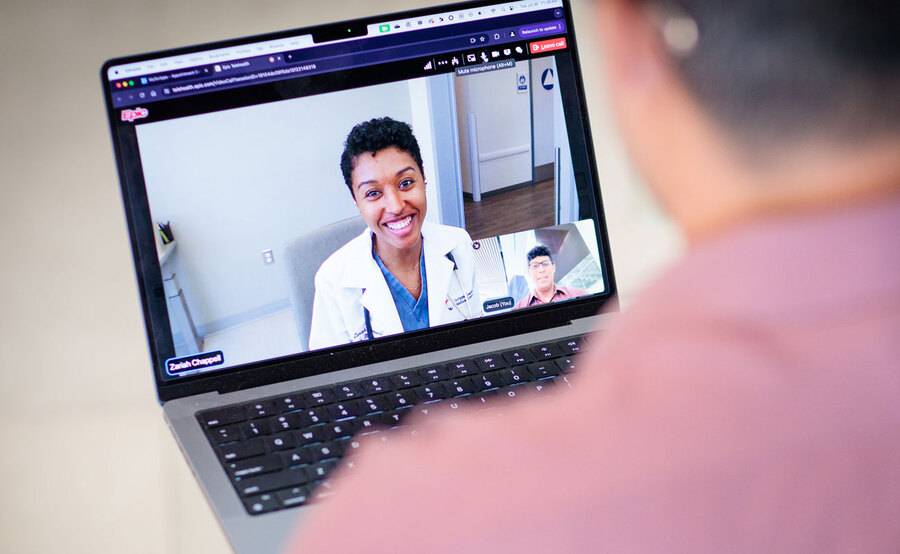 A female doctor smiles at a patient from a laptop screen, representing telemedicine options at Scripps Health.