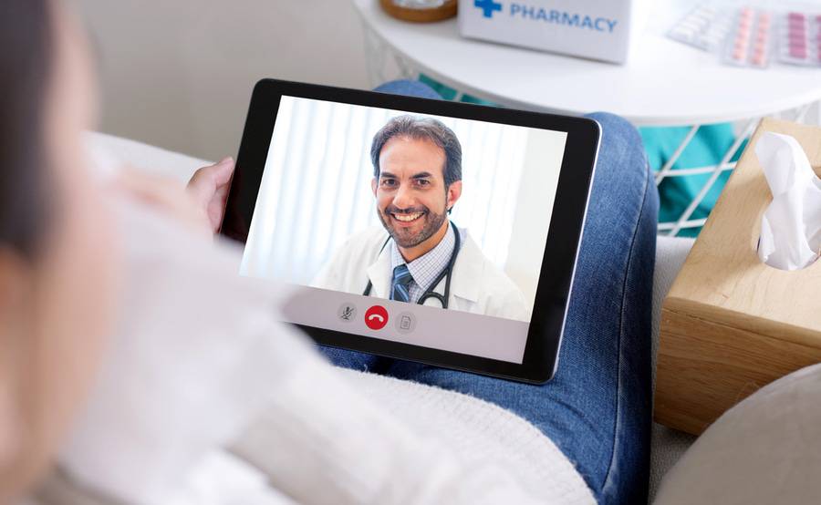 A male doctor smiles at a patient from a tablet screen, representing telemedicine options at Scripps Health.