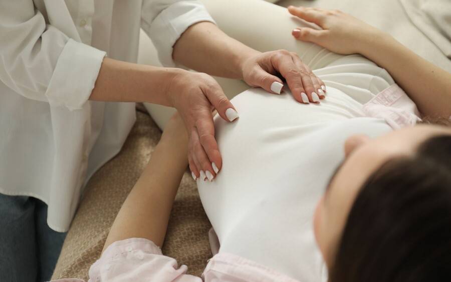 A pregnant woman gets help from a midwife.