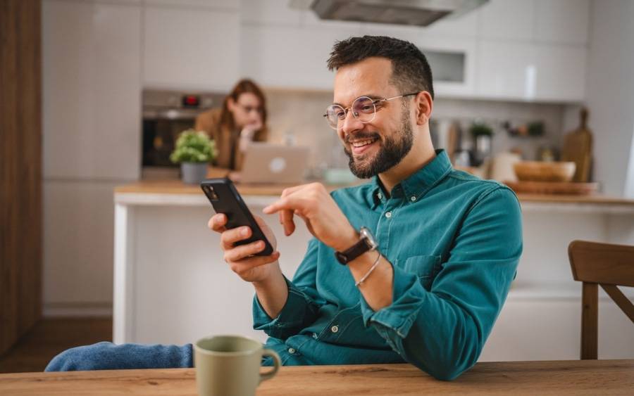 An adult man checks  his phone for information on preventive health screenings.