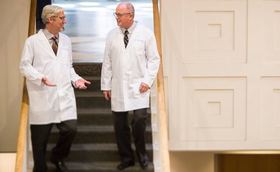 Two surgeons in white coats talk with one another, representing the liver transplant program at Scripps Health.