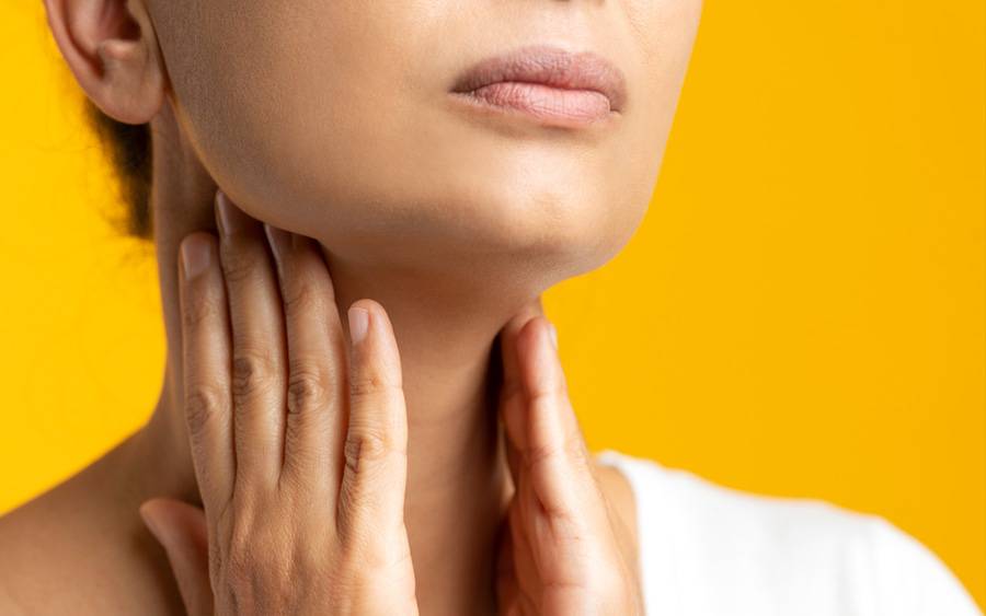 A woman feels her neck area for signs of thyroid problems.