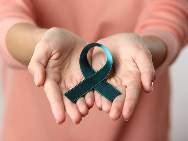 A woman holds a ribbon symbolizing ovarian cancer awareness.