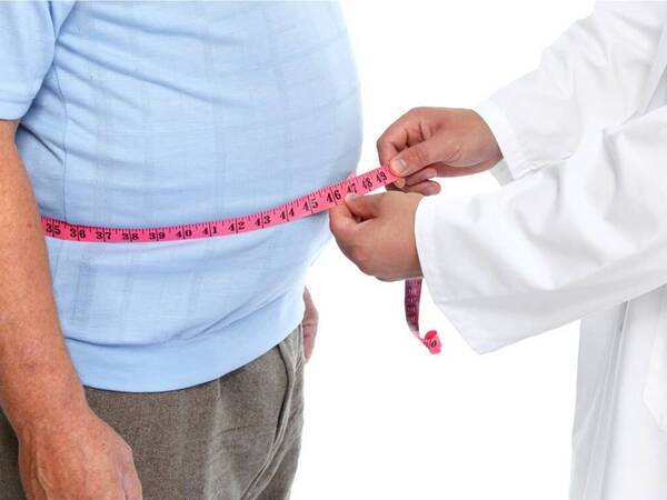 A provider uses a tape measure around a patient's midsection.