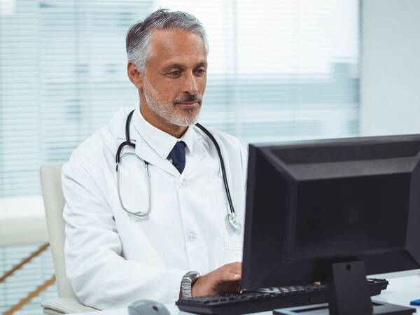 A male doctor sits at the computer while participating in a speaker series.