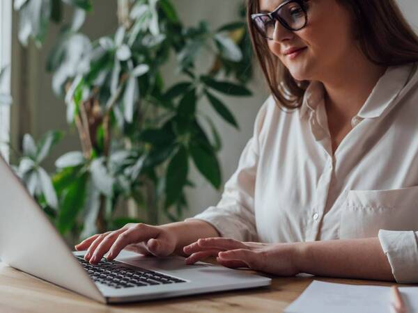 A young woman types on a laptop keyboard.