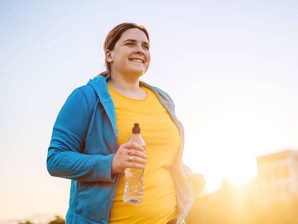 A young woman jogs in the early morning sunlight.