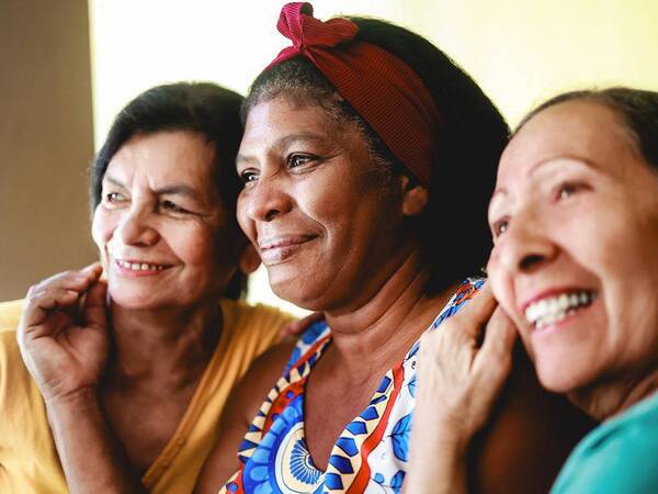 Three senior women smile as they participate in a group session for stroke and brain injury survivors.