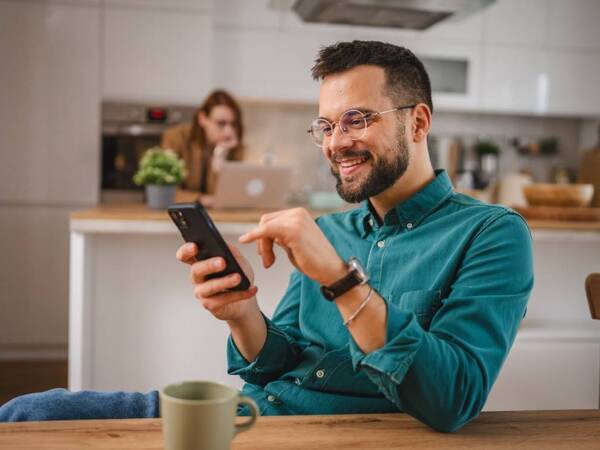 An adult man checks  his phone for information on preventive health screenings.