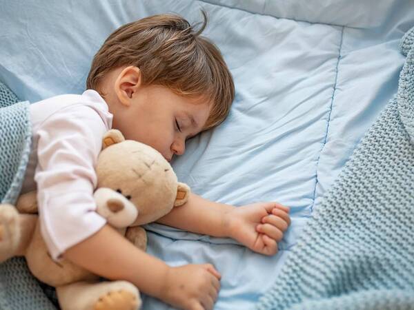 A little boy sleeps well with his teddy bear.