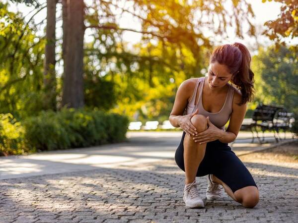 A runner rubs her knees after feeling pain during a workout. Could it be early onset knee osteoarthritis?