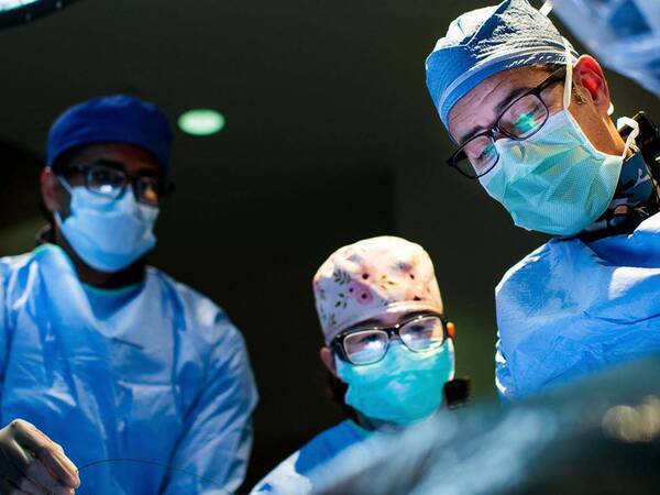 Surgeons and staff work on a patient in an operating room.