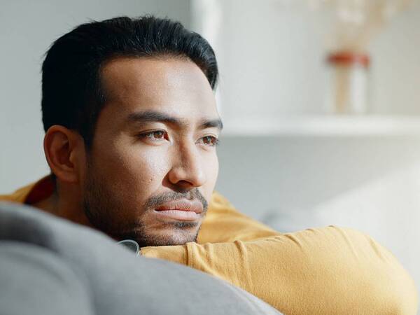 A middle-aged man rests his head on his arm looking sad.