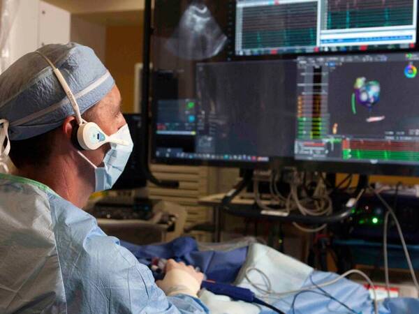 A surgeon monitors a patient's lung activity after receiving a pacemaker on multiple computer screens.