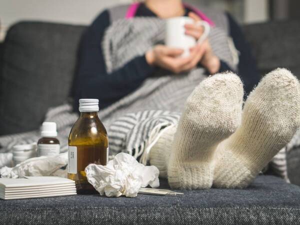 A woman with a contagious illness isolates at home with medicines to prevent spread of illness.