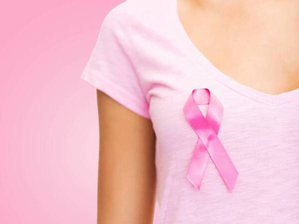 A young cancer survivor wears a pink ribbon on her shirt.