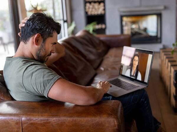 A man sitting in his living room conducting a Video Visit with his provider.