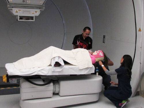 Scripps Health physician Andrew Chang helps prepare pediatric cancer patient Natalie Wright for her proton therapy treatment.