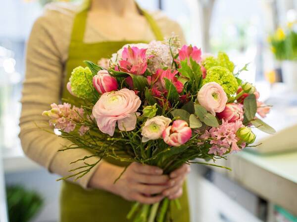 A florist presents a fresh bouquet of flowers representing the floral services offered at Scripps Hospital gift shops.